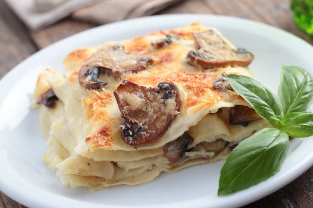 Porzione di lasagna con funghi e salsiccia