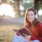 Donna legge un libro in un parco mentre ascolta la musica