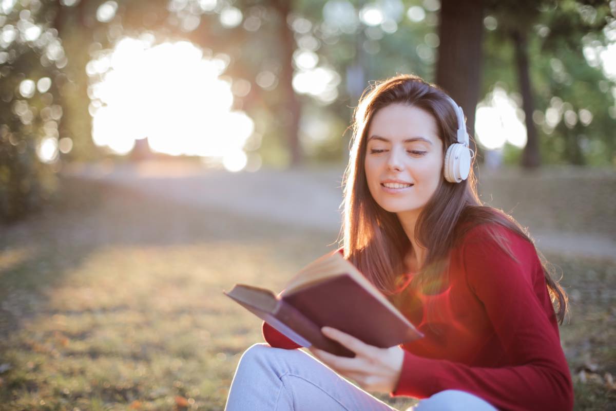 Donna legge un libro in un parco mentre ascolta la musica