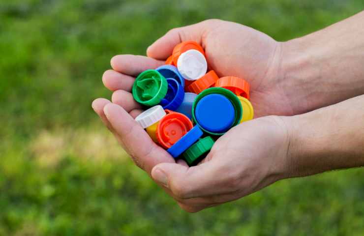 tappi di plastica colorati in mano
